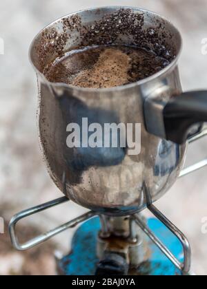 Isolierte Nahaufnahme einer kochenden schwarzen Kaffeekanne auf einem Gasherd im Freien - Israel Stockfoto