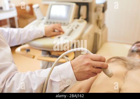 Nahaufnahme des nicht erkennbaren Sonografen mit Ultraschallsonde beim Überprüfen des Bauchs des Patienten Stockfoto