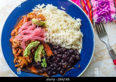 Cochinita Pibil, mexikanisches, pit-geröstetes Schweinefleischgericht von der Halbinsel Yucatan, serviert mit Reis, Bohnen und traditionellen Gewürzen. Tacos aus Mexiko. Stockfoto