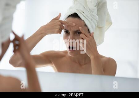 Umgekippte Frau sieht im Spiegel, drückt den Zuhälter auf die Stirn Stockfoto