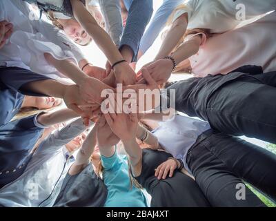 Befreundete Freunde schließen sich als Zeichen des gemeinsamen Geschäftes an. Das Konzept von Team und Community. Stockfoto
