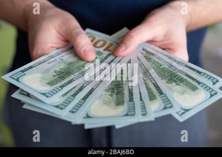 Dollar in den Händen des Mannes. Gewinne, Ersparnisse. Erfolg, Motivation, Finanzströme, Wohlstand. Stapel von Dollars. 100 US-Dollar Stockfoto