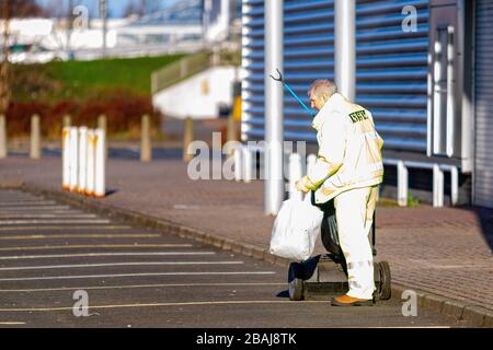 Glasgow, Schottland. März 2020. Eine einsame Figur, die in einem verlassenen Einzelhandelspark Colin Poultney/Alamy Live News Müll anderer Menschen sammelt Stockfoto