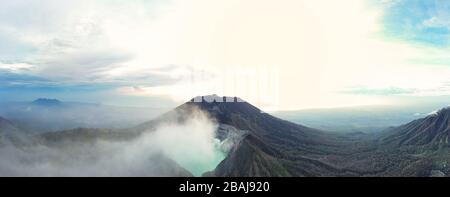 Panoramablick auf den Vulkan Ijen mit dem türkisfarbenen sauren Kratersee bei Sonnenaufgang. Stockfoto