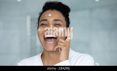 Fröhliche afrikanerin, die während der morgendlichen Routine der Hautpflege singt Stockfoto