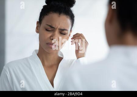 Bei der Reinigung von Ohren durch Afrikanerin wird Ohrenschmalz als Unbehagen und Schmerzen empfunden Stockfoto