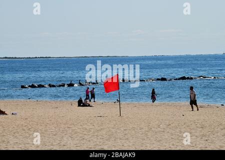 Coney Island, New York, USA-September 2019; Blick auf eine rote Fahne am Strand während der Absaison Ruhe am Strand von Coney Island mit Menschen Stockfoto