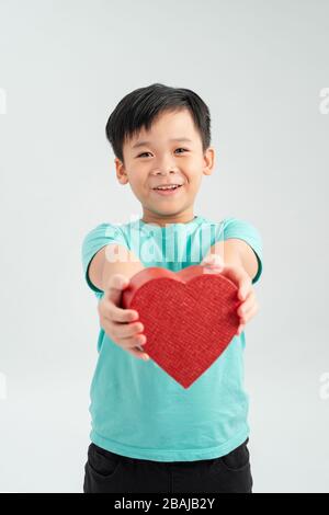 Fröhlicher Junge in der Liebe, der einen herzförmigen Geschenkkasten hält Stockfoto