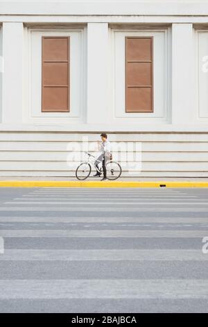 Überall von seinem Fahrrad. Seitenansicht der junge Unternehmer freuen uns auf dem Fahrrad Stockfoto