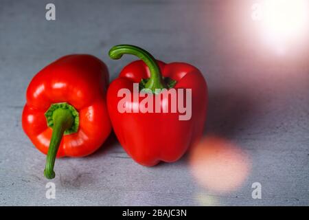 Zwei rote Paprika auf einem grauen Tisch Stockfoto