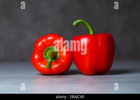 Zwei rote Paprika auf einem grauen Tisch Stockfoto