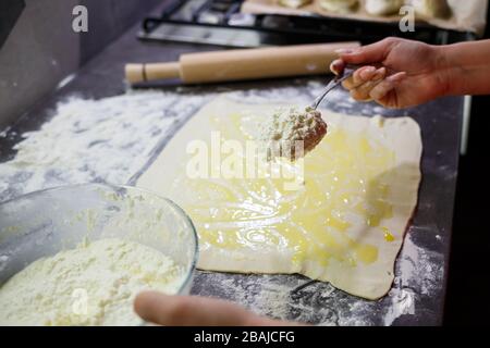 Backen von heimischen Brötchen mit Käse. Käse für Brötchen auf Teig legen Stockfoto