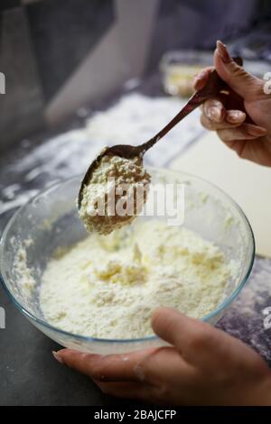 Backen von heimischen Brötchen mit Käse. Käse für Brötchen auf Teig legen Stockfoto