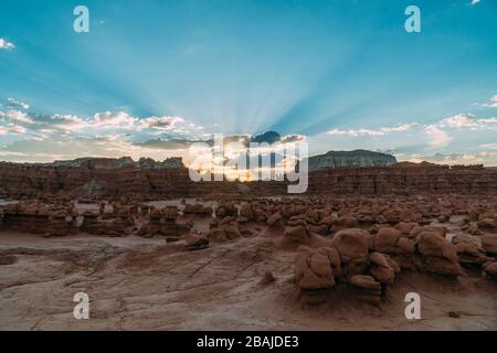 Wunderschöner Blick auf den Sonnenaufgang auf den Goblin Valley State Park, Utah, mit Lichtstrahlen, die hinter den großen pilzförmigen Felsen ihren Höhepunkt erreichen. Stockfoto