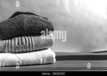 Stapel von Wollpullover im Schwarz-Weiß-Modus. Slow Fashion Konzept mit Platz für Text Stockfoto