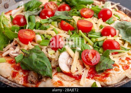 Frische rohe Pizza mit Pilzen, Kirschtomaten, Basil und Parmesan. Hausgemachte Pizza vor dem Backen Stockfoto