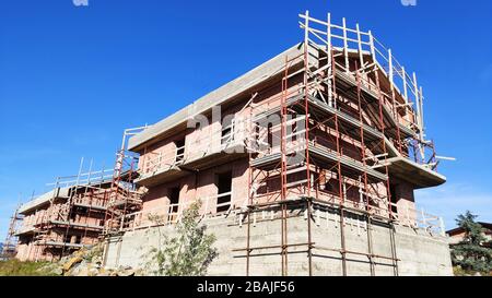 Rekonstruktion von Häuserblocks mit Gerüstgerüst vor dem Haus. Umbauarbeiten mit Gerüsten. Zusammensetzung für Bauunternehmen. Sym Stockfoto