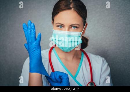 Schutz vor Coronavirus. Junge Frau Doktor in weißer Uniform mit Maske und Handschuhen. Stockfoto