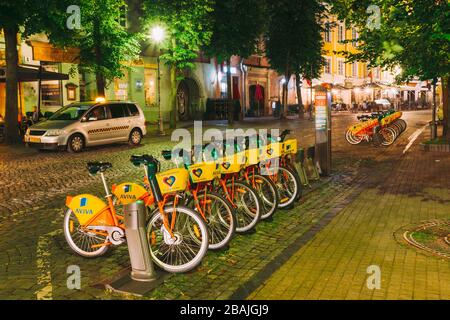 Vilnius, Litauen - 5. Juli 2016: Reihe bunter Fahrräder AVIVA zum Mieten auf dem städtischen Fahrradparkplatz in der Straße. Sommernacht. Stockfoto