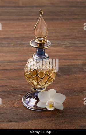 Traditionelle arabische Parfüm-Flasche mit einer weißen Orchideenblüte Stockfoto