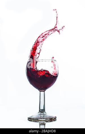 Glas spritzt Rotwein mit weißer Hintergrundfeier Stockfoto