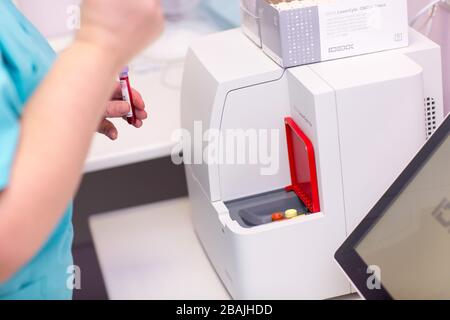 Blutanalysator. Laborassistent im medizinischen Labor hält Reagenzglas mit Blut und Plasma in der Hand und führt Analysen durch. Stockfoto