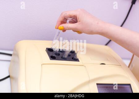 Blutanalysator. Laborassistent im medizinischen Labor hält Reagenzglas mit Blut und Plasma in der Hand und führt Analysen durch. Stockfoto