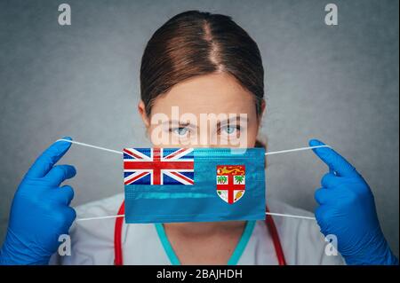 Coronavirus in Fiji, Female Doctor Portrait Hold Protect Face Surgical Medical mask with Fiji National Flag. Krankheit, Virus Covid-19 n Fiji, Konzept p Stockfoto