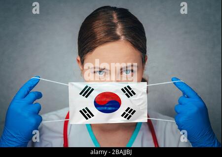 Coronavirus in Südkorea Female Doctor Portrait Hold Protect Face Surgical Medical mask with South Korea National Flag. Krankheit, Virus Covid-19 in S Stockfoto