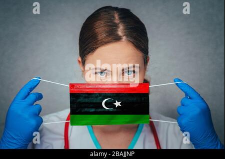 Coronavirus in Libyen Female Doctor Portrait Hold Protect Face Surgical Medical mask with Libya National Flag. Krankheit, Virus Covid-19 in Libyen, Schein Stockfoto