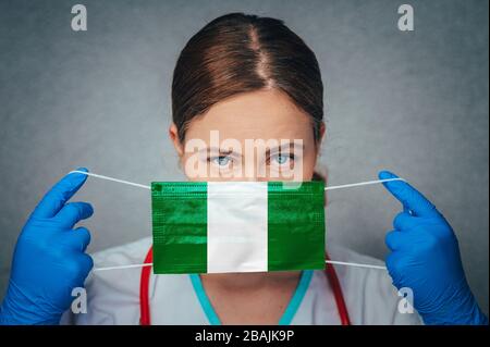 Coronavirus in Nigeria Female Doctor Portrait Hold Protect Face Surgical Medical mask with Nigeria National Flag. Krankheit, Virus Covid-19 in Nigeria, Stockfoto