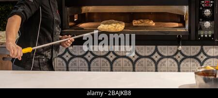 Baker backt Focaccia mit elektrischem Ofen Stockfoto