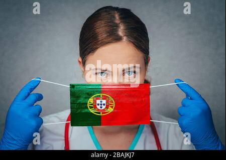 Coronavirus in Portugal Female Doctor Portrait Hold Protect Face Surgical Medical mask with Portugal National Flag. Krankheit, Virus Covid-19 in Portuga Stockfoto
