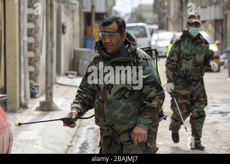 Bagdad, Irak. März 2020. Irakische Zivilschutzarbeiter tragen Schutzanzüge, wenn sie Desinfektionsmittel in einem Wohngebiet sprühen, um die Ausbreitung von Coronavirus zu bekämpfen. Credit: Ameer Al Mohammadaw / dpa / Alamy Live News Stockfoto