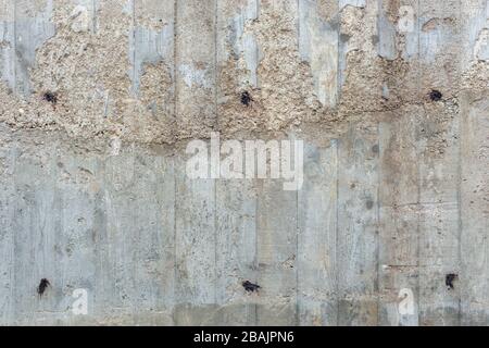 Eine dicke raue graue Betonwand im Freien mit sichtbaren Abdrücken von Holzbohlen, doppelt gefüllt Stockfoto