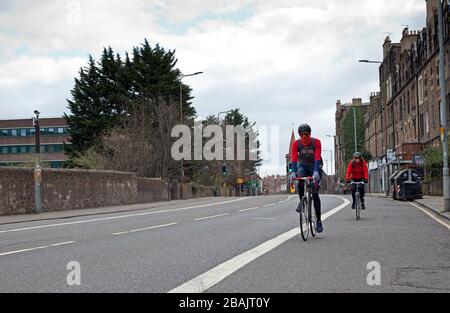 Edinburgh, Schottland, Großbritannien. März 2020. Coronavirus-Effekt, um 11 Uhr Samstag, verlassene Straßen und zwei Radfahrer halten einen sicheren Abstand voneinander Reisen von Willowbrae in Richtung Meadowbank Bezirk und erhalten eine freie Straße, um ihre Zeit der erlaubten Bewegung zu nehmen. Stockfoto