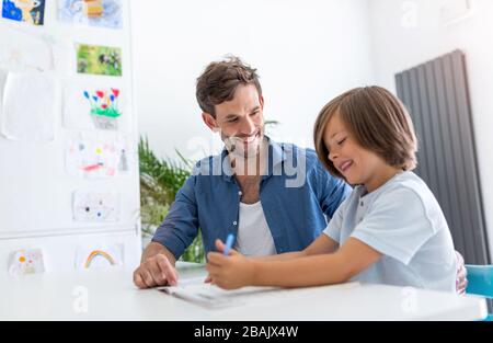 Vater und Sohn gemeinsam Hausaufgaben zu machen wie zu Hause. Stockfoto