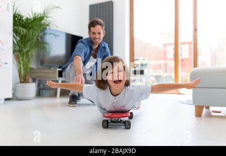 Vater schiebt Sohn auf Skateboard Stockfoto
