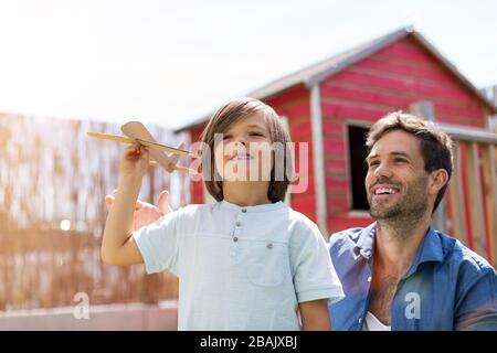 Vater und Sohn spielen zusammen mit einem Papierspielzeugflugzeug Stockfoto