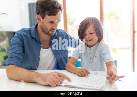 Vater und Sohn gemeinsam Hausaufgaben zu machen wie zu Hause. Stockfoto