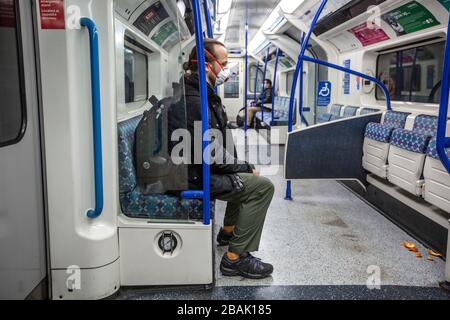 Ein Mann, der in der Londoner U-Bahn eine Maske mit Atemschutzmaske trägt, da Pendler zu den am meisten gefährdeten Personen gehören, die Coronavirus-Infektion zu verbreiten Stockfoto