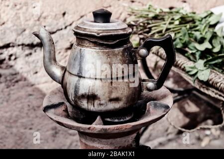 Alte rostige Teekanne mit marokkanischer Minze. Vintage-Bild mit Filmkörnung. Stockfoto