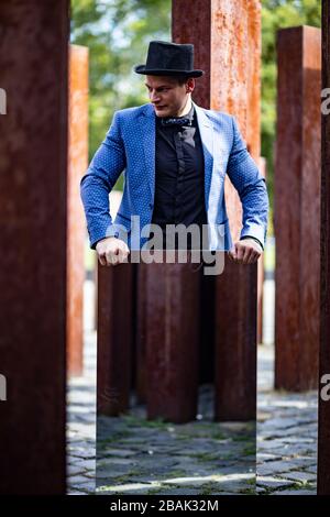 Porträt eines jungen männlichen Athleten in elegantem, stilvollem Outfit unter rohen, rostigen Eisenpfosten Stockfoto