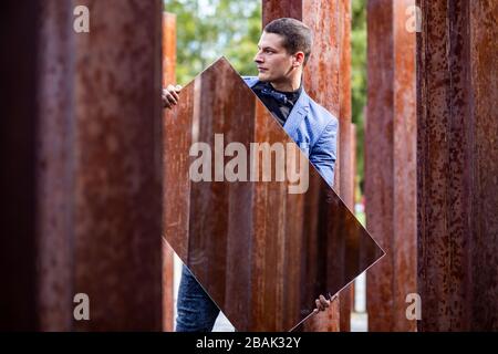 Porträt eines jungen männlichen Athleten in elegantem, stilvollem Outfit unter rohen, rostigen Eisenpfosten Stockfoto