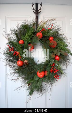 Schöner Weihnachtskranz mit Beeren und Obst an der Haustür Stockfoto