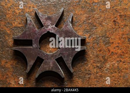 Hintergründe und Texturen: Rostiger sechszackiger Stern oder Kreuz aus Stahl, auf stark korrodierter Metalloberfläche Stockfoto