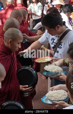 Touristen, die während des weltweit größten Mittagessen buddhistischer Mönch im Mahagandayon-Kloster Mandalay in Myanmar Essen verteilen Stockfoto