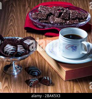 Süßigkeiten mit Kaffee- oder Teetasse und Untertasse auf Hardcover-Buch Stockfoto