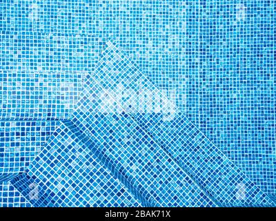 Das Licht, das auf der Oberseite der Wasseroberfläche des Pools reflektiert wurde, war unten mit blauen Mosaikfliesen ausgekleidet. Das Wasser wellt sich auf der Rückseite des blau gefliesten Schwimmbads Stockfoto