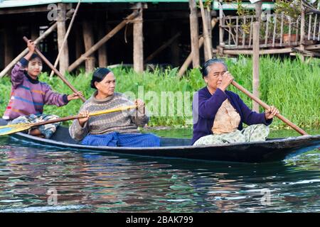 Birmanerinnen und Mädchen rudern auf einem Boot, Inle Lake, Myanmar Stockfoto